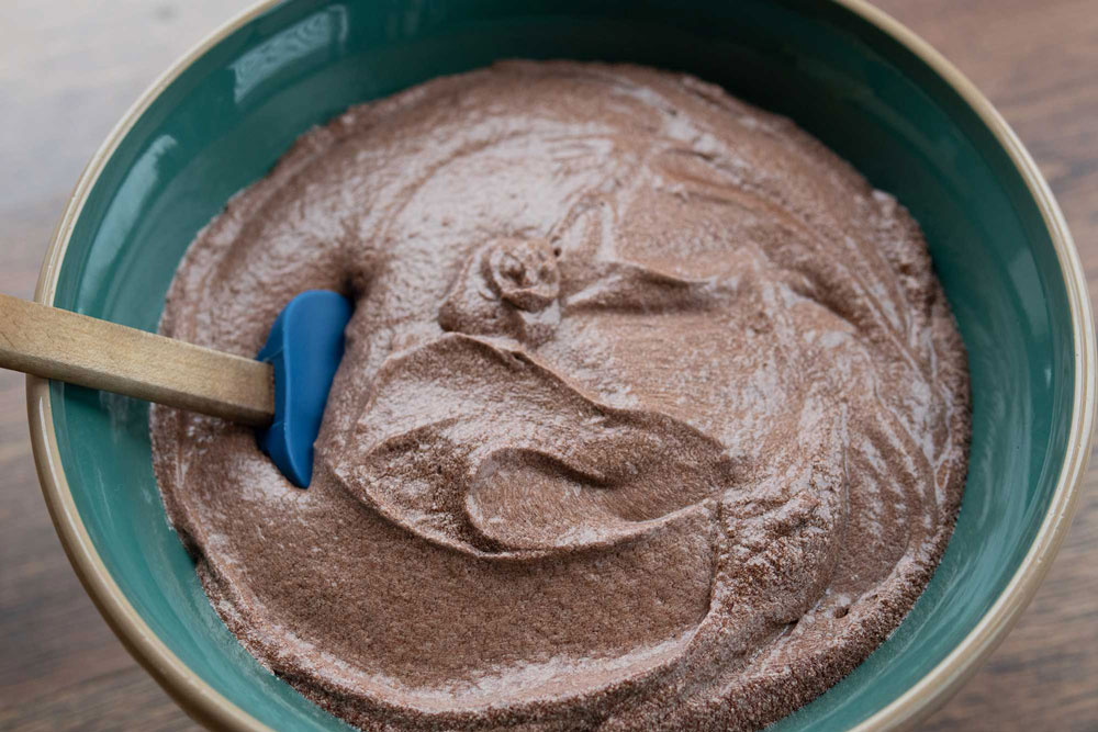 chocolate cake batter in a mixing bowl with a rubber spatula