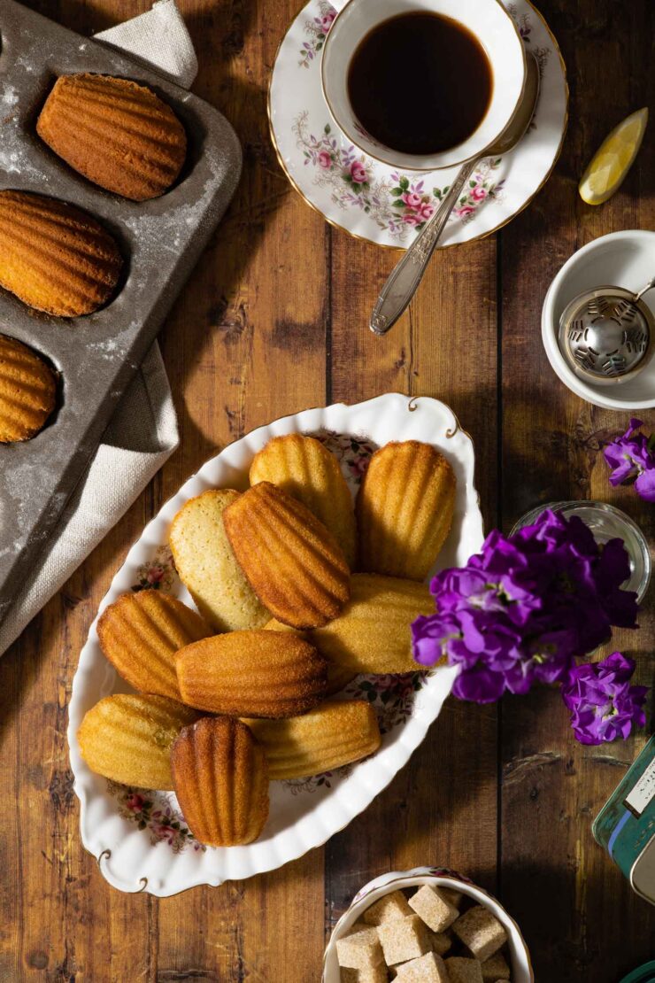 earl grey madeleines on a platter with a tea set and flowers