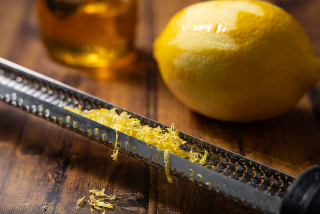 lemon zest on a microplane, a jar of honey, and a lemon