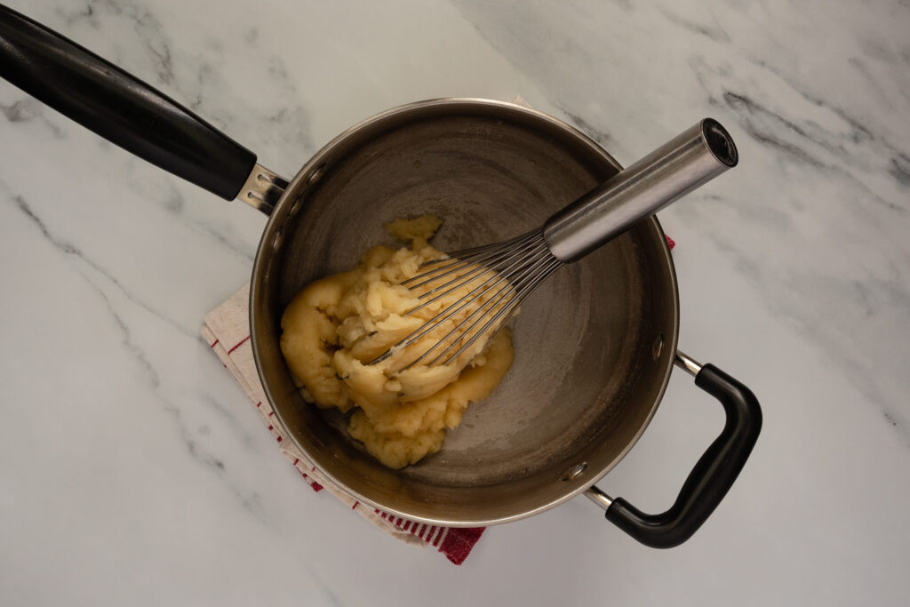 Choux paste in a saucepan with a whisk