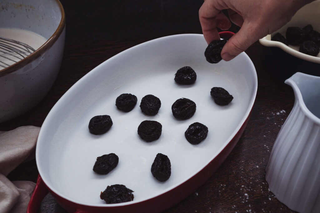 putting brandy-soaked prunes in a baking dish