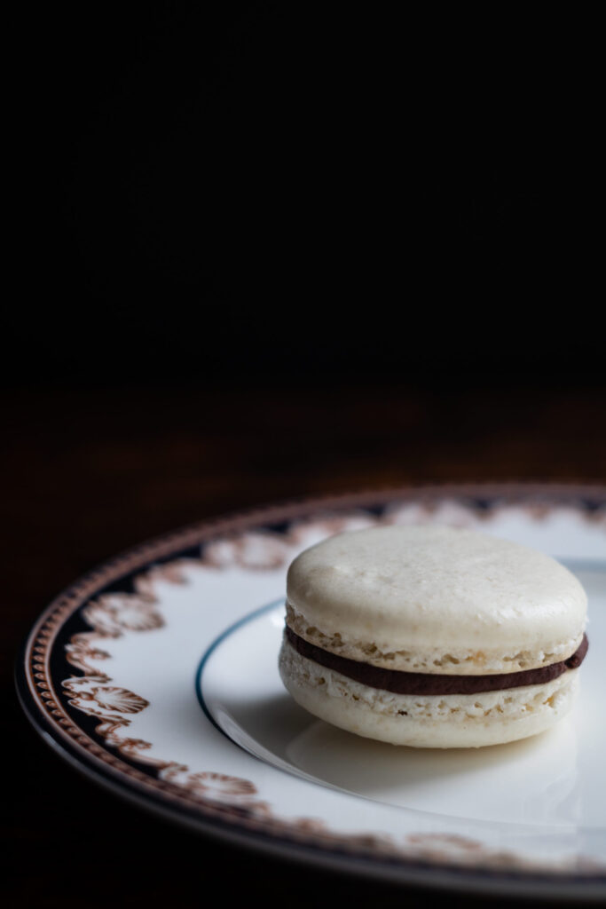 almond macaron with dark chocolate ganache on porcelain plate