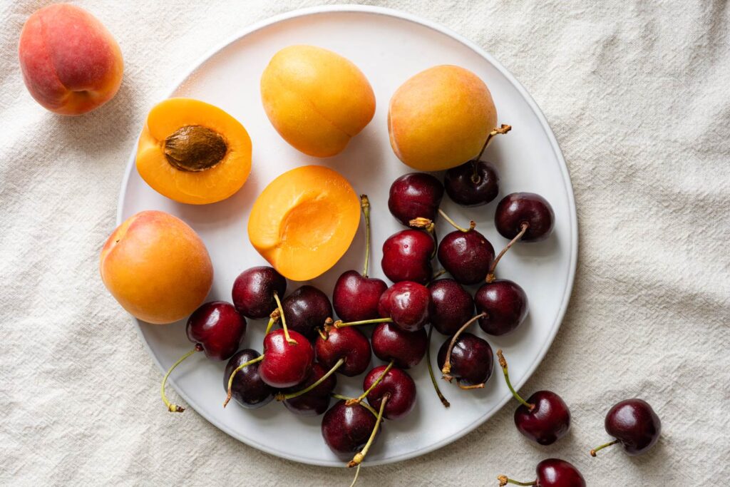 sweet cherries and fresh apricots on a white plate