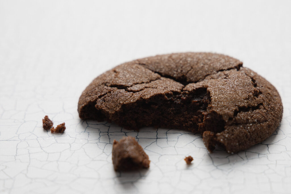 chocolate buckwheat cookie with a bite missing and crumbs on a white background