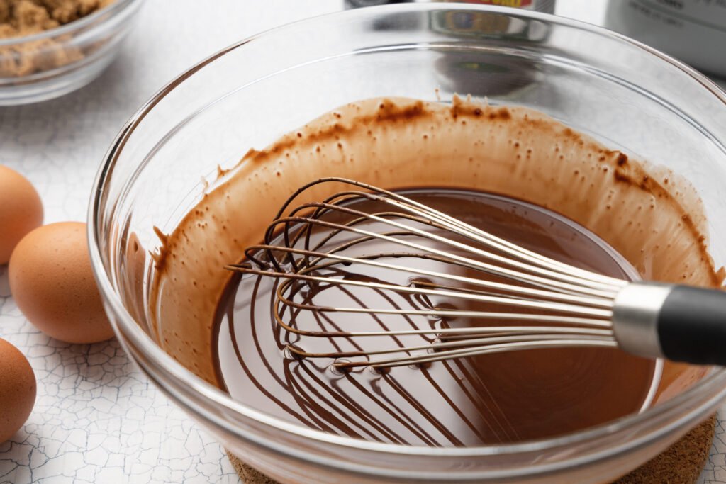 melted butter and chocolate in a glass bowl with a whisk