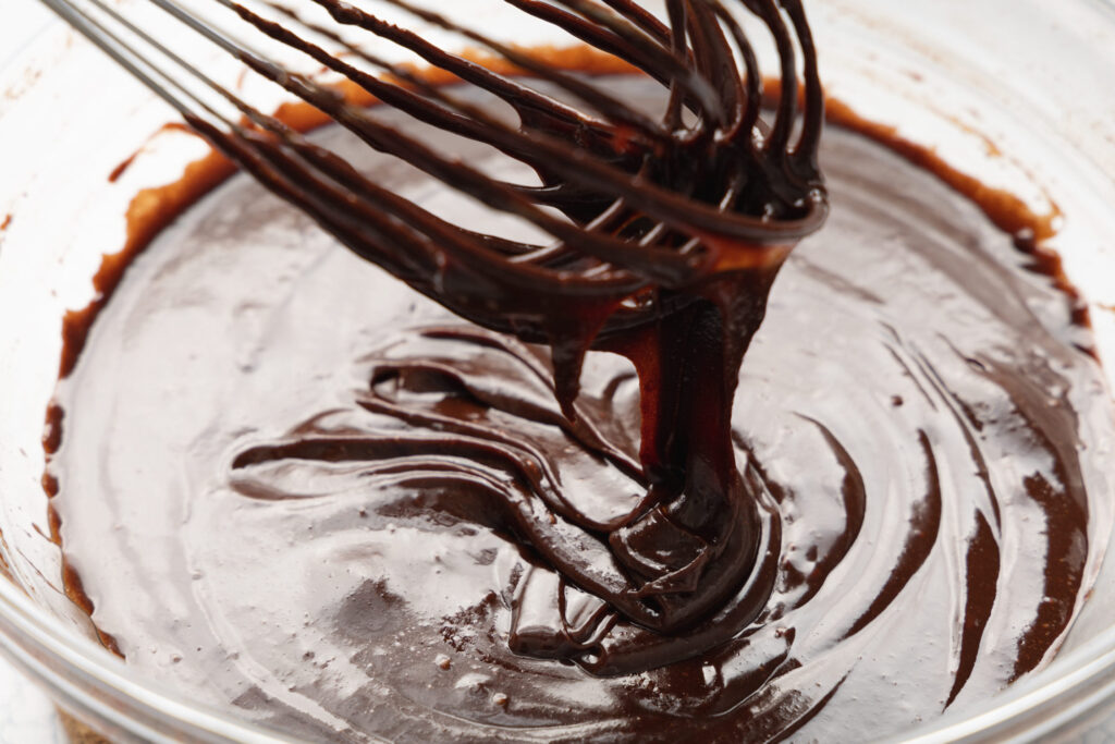 chocolate batter in a glass mixing bowl with a whisk
