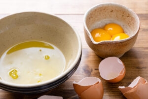 Eggs separated into two ceramic bowls — whites in a wide bowl and yolks in a smaller one, shells nearby
