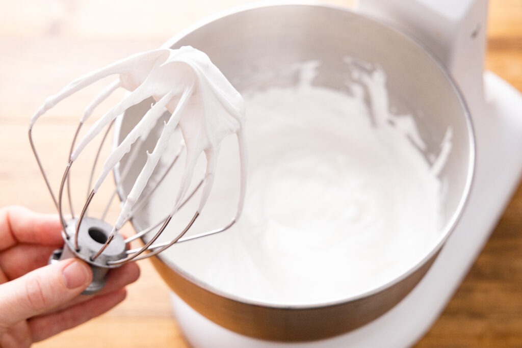 whipped egg whites illustrating stiff peaks on a whisk