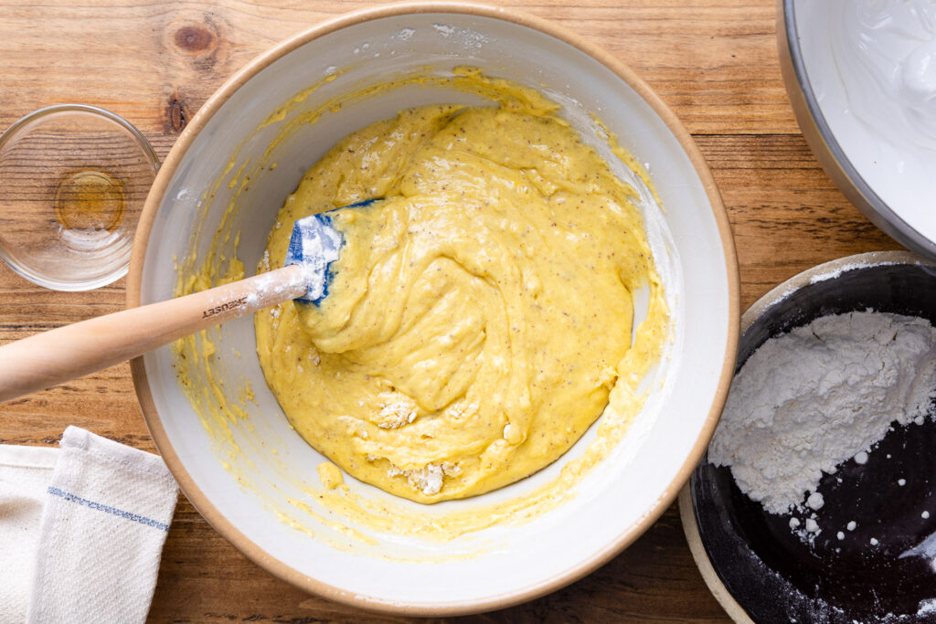 adding the flour into the cake batter in a large mixing bowl