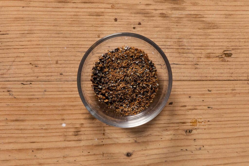 Coarsely ground cardamom seeds in a small glass bowl to show how fine to grind the cardamom