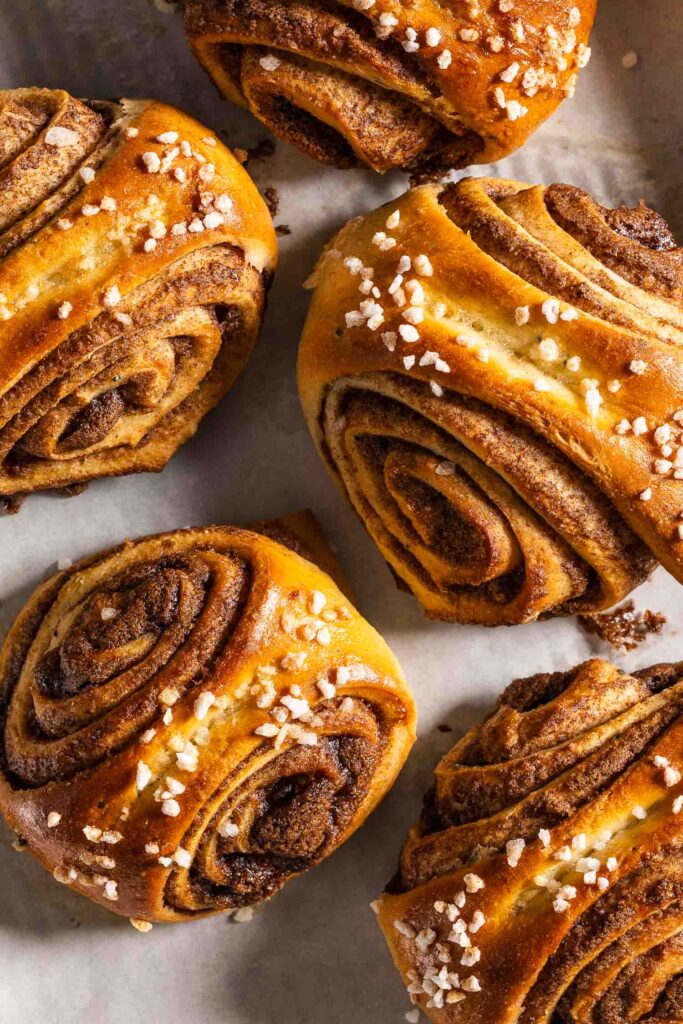 Baked korvapuusti cinnamon buns on a baking sheet lined with parchment paper