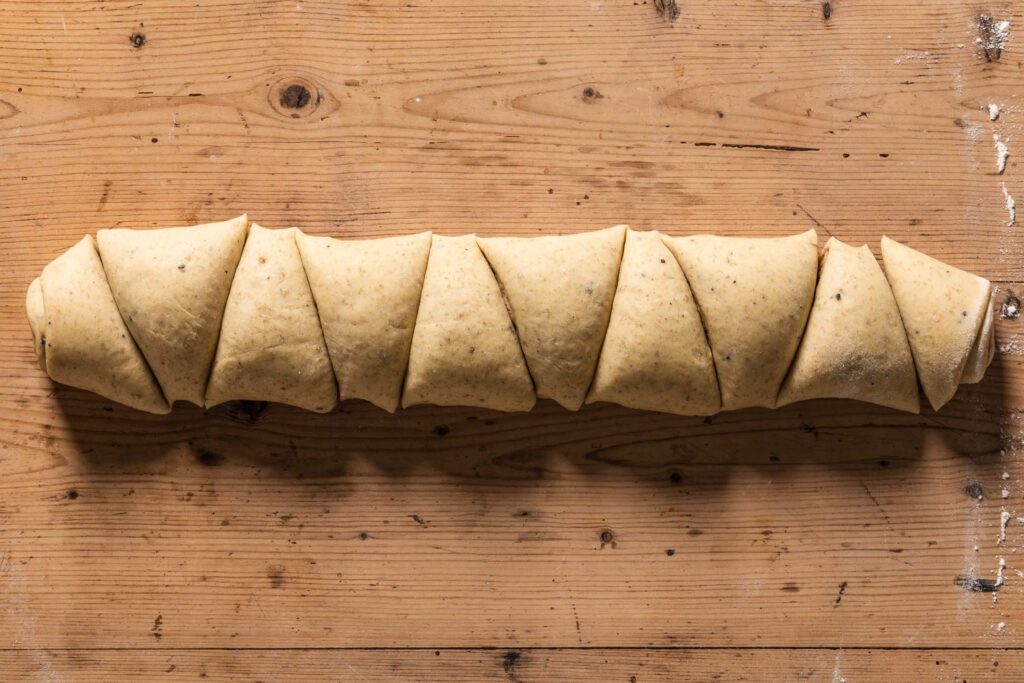 An overhead photo of the rolled, unbaked cinnamon buns, cut into triangular portions