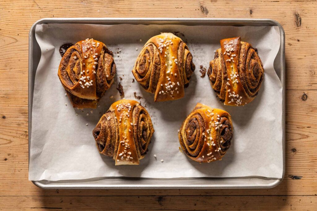 Baked korvapuusti cinnamon buns on a baking sheet lined with parchment paper