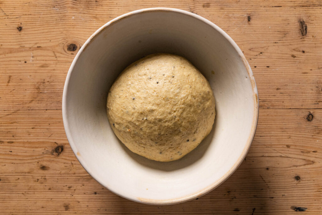 An overhead photo of the dough in a ceramic mixing bowl after kneading and before bulk fermentation