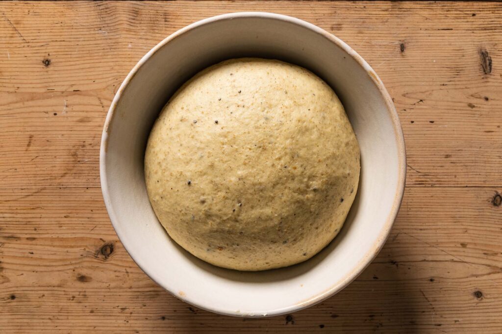 An overhead photo of the dough in a ceramic mixing bowl after bulk fermentation