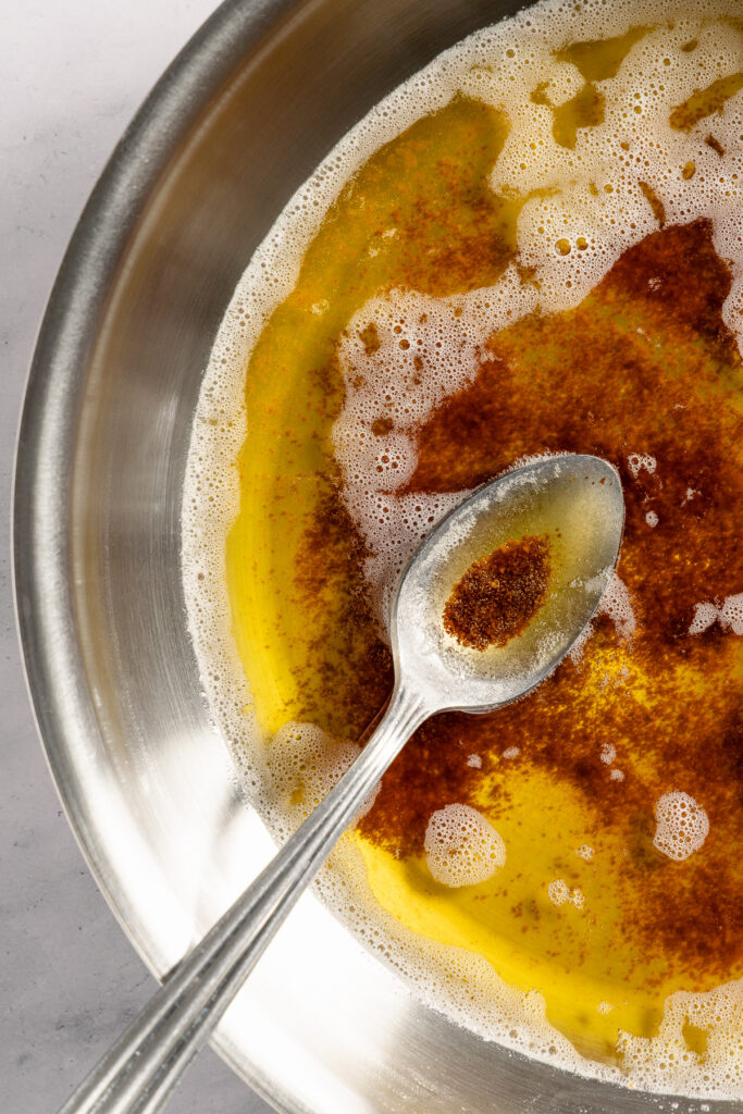 Brown butter in a spoon over a light-colored sauté pan