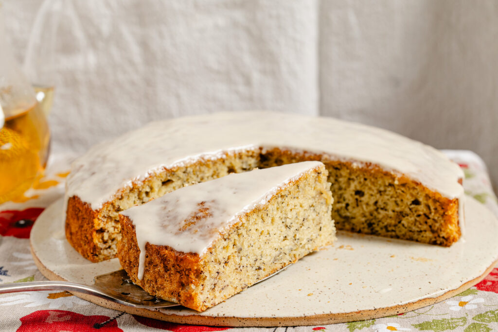 Cross-section of moist olive oil banana cake with chamomile glaze on speckled plate